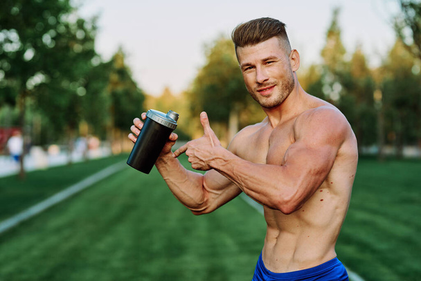 athletic man with pumped up muscular body in the park exercise workout motivation - Foto, Bild