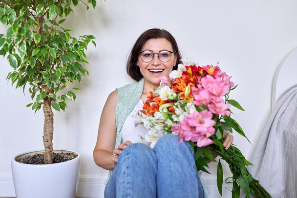 Portrait of a happy middle-aged woman with a bouquet of flowers - Fotografie, Obrázek