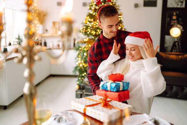 Young couple with Christmas gifts at home near Christmas tree. Romantic day. Winter holidays. New Years. - Foto, imagen