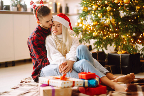 Young couple with Christmas gifts at home near Christmas tree. Romantic day. Winter holidays. New Years. - Fotografie, Obrázek