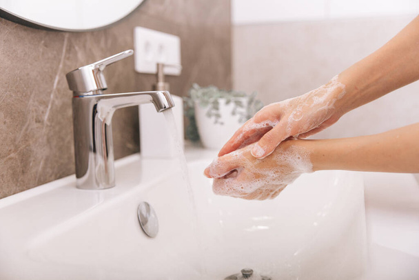 Washing hands under the flowing water tap. Washing hands rubbing with soap for corona virus prevention, hygiene to stop spreading corona virus in or public wash room. Hygiene concept hand detail - Foto, imagen