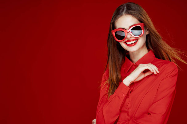 beautiful woman wearing sunglasses red shirt makeup isolated background - Foto, afbeelding
