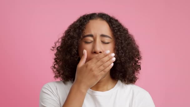 Sleepy zwarte jonge dame geeuwen bedekken mond over roze achtergrond - Video
