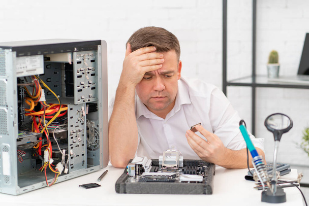 computer workshop. professional services. sad repairman with a processor in hand - Φωτογραφία, εικόνα