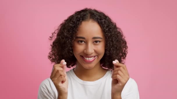 Africká žena ukazuje srdce symbol s prsty přes růžové pozadí - Záběry, video