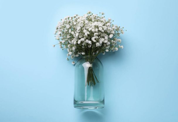 Bouquet of white gypsophila in glass vase on light blue background, top view - Fotoğraf, Görsel