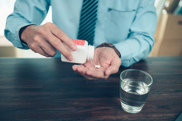 Businessman working with glass of water takes  pills in hand. Working and sick concept. - Foto, Imagen