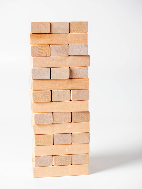 Primer plano de un juego de jenga hecho de bloques de madera sobre un fondo blanco. Vista lateral - Foto, imagen