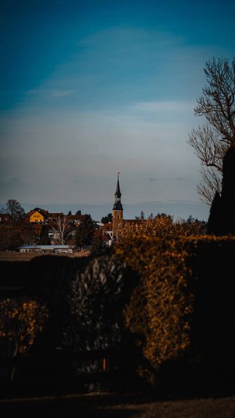 A tall clock tower with a cross in a town - Fotoğraf, Görsel