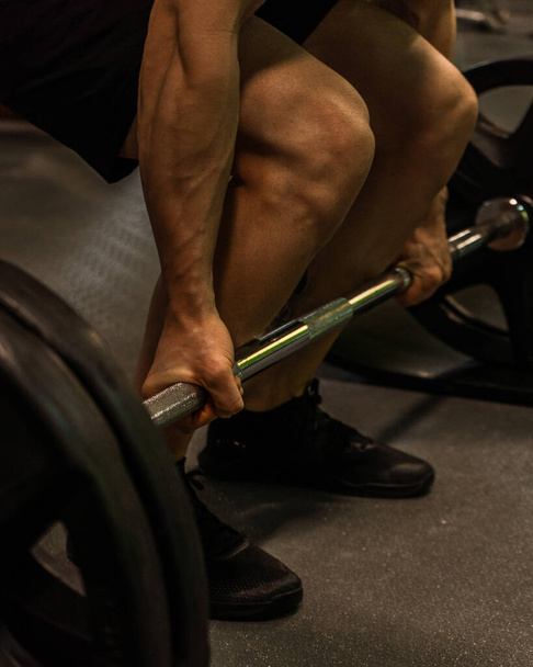 A vertical shot of a muscular guy lifting weights - Фото, изображение