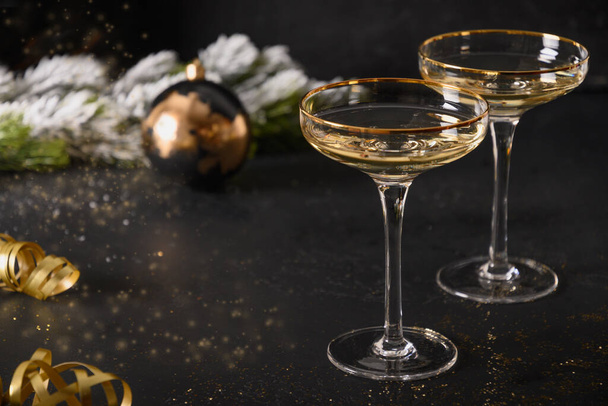 Festive New Year champagne flutes and Christmas gold baubles on black background. - Fotoğraf, Görsel