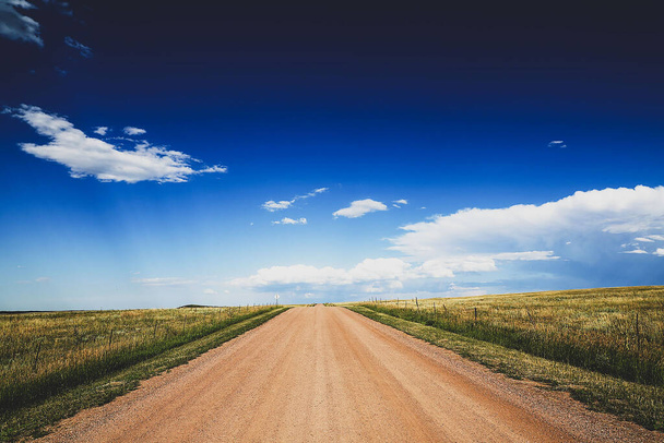 A mesmerizing shot of a long road in the middle of huge fields - Foto, Bild