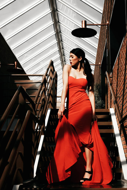 A vertical shot of an East Asian girl wearing a beautiful red dress - Fotografie, Obrázek