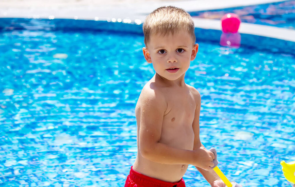 Happy child in the pool playing with a water gun. Recreation - 写真・画像