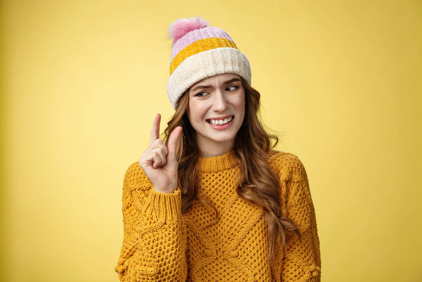Displeased attractive picky woman describing small object show tiny thing cringing dislike disappointment look upset fingers, describing little salary new job, standing yellow background awkward - Foto, imagen