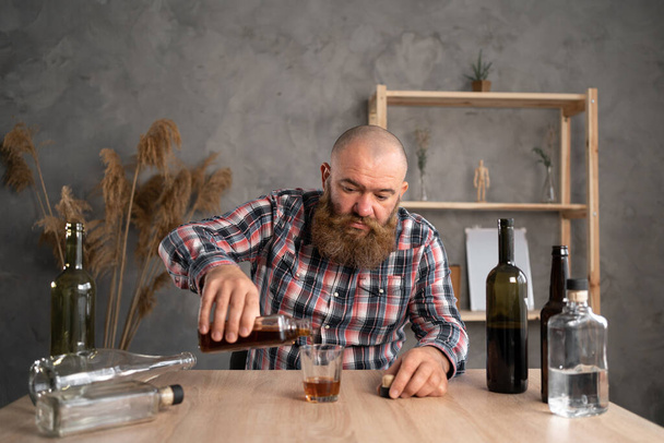 Milenyum sakallı alkolik adam evde viski içiyor. Alkol bağımlılığı. Sorun ve depresyon. Alkolizm Tedavisi. - Fotoğraf, Görsel
