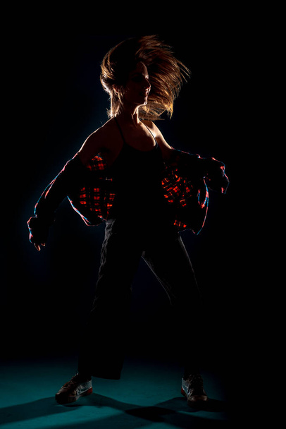 Fit genç dansçı kız karanlık stüdyoda izole edilmiş bir dans gösterisi yapıyor. - Fotoğraf, Görsel