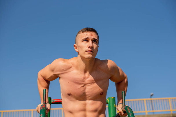 Attractive and handsome guy is focusing on the exercise while being topless - Fotó, kép