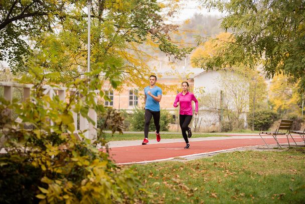 Attractive and sportive couple is running together in the park - Foto, Bild