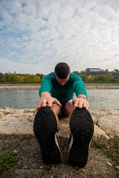 Attractive and handsome guy is stretching himself by the river, in the morning - Fotó, kép