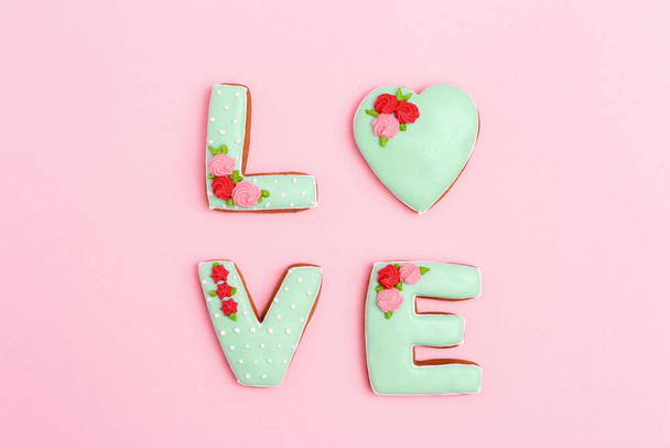 Gingerbread heart, cookies in shape of letter love with icing on pastel pink background. Valentines day composition or greeting postcard with copy space for text. Minimal style. - Fotoğraf, Görsel