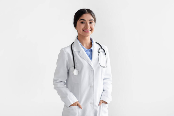 Porträt einer selbstbewusst lächelnden indischen Ärztin im weißen Mantel mit Stethoskop - Foto, Bild