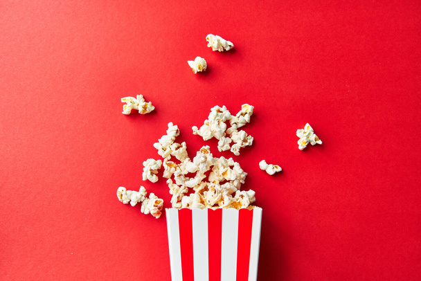 Egy csomag sós popcorn esik a piros háttér - Fotó, kép
