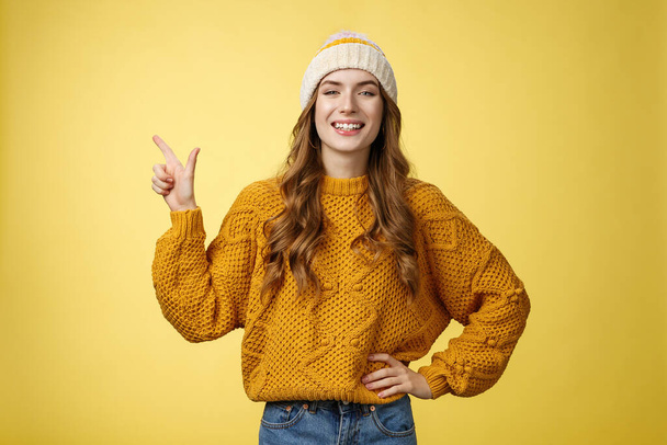 Pewny siebie modny 20s dziewczyna dumnie uśmiechnięty trzymać talię pewny siebie wskazując lewy górny róg pokazując idealne miejsce kopia top reklama, promując produkt grinning zachwycony - Zdjęcie, obraz