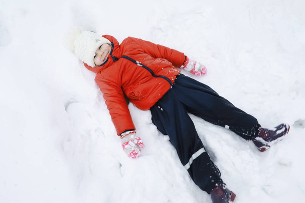 Gyerekek a parkban télen. A gyerekek hóval játszanak a játszótéren. Hóembert faragnak, és lecsúsznak a hegyeken.. - Fotó, kép