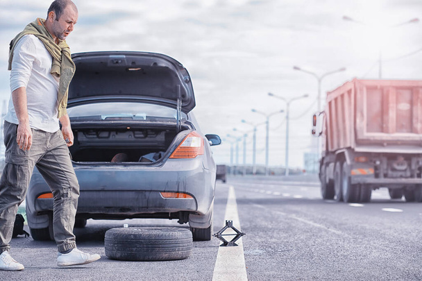 Replacing the wheel of a car on the road. A man doing tire work on sidelines. - Fotoğraf, Görsel