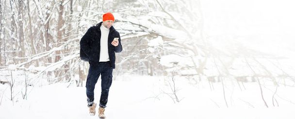 Un homme en hiver dans la forêt. Un touriste avec un sac à dos traverse les bois en hiver. - Photo, image
