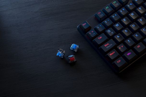 schwarzer Holztisch mit Gamer-Tastatur und farbigen Schaltern - Foto, Bild