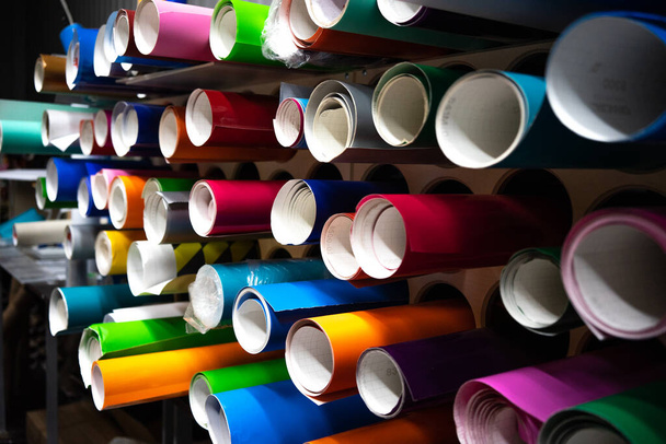 Vinylfolie in verschiedenen Farben in runden Röhren. Werbeproduktion. Ein Geschäft mit selbstklebenden Folien. - Foto, Bild
