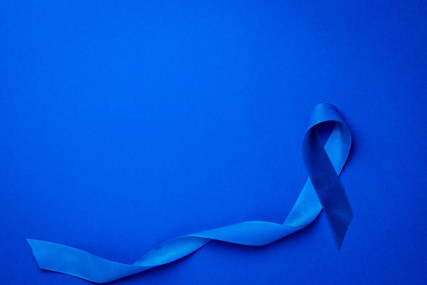 Noviembre. Sensibilización sobre la salud de los hombres en noviembre con cinta azul para el cáncer de próstata aislada sobre fondo azul profundo. - Foto, Imagen
