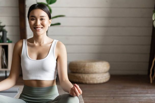 Concetto di consapevolezza e meditazione. Giovane donna asiatica che fa allenamento a casa, meditazione yoga in soggiorno sul tappetino, concentrandosi - Foto, immagini