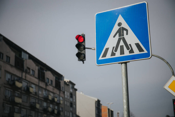 A low angle shot of a pedestrian cross sign and red traffic lights in a street - Foto, Bild
