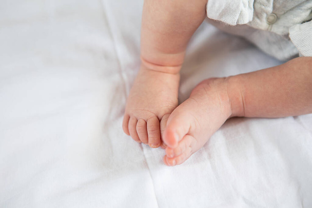 Маленькие ноги новорожденного ребенка на кровати, вид сверху. Концепция материнства, грудного вскармливания - Фото, изображение