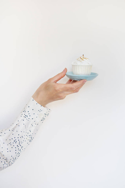 A female hand holds a delicious cupcake, congratulations on a happy birthday. Place for an inscription - Foto, imagen