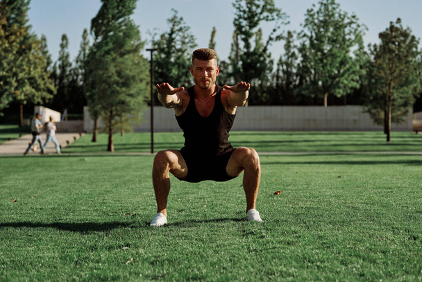 sports man doing exercises on the lawn in the park - Photo, image