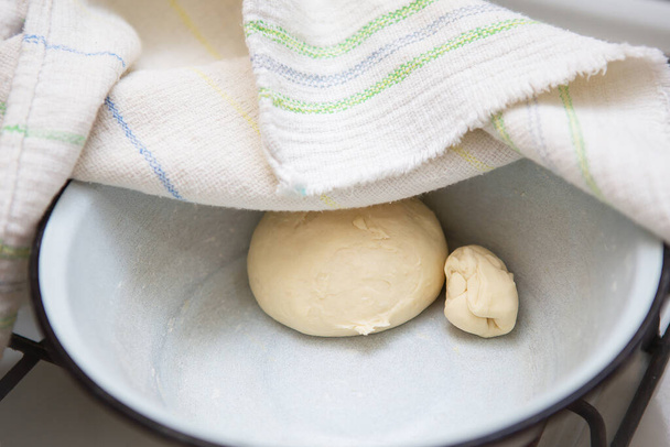 Preparación de masa para hacer albóndigas, ravioles, manti, albóndigas. La masa en el plato bajo la toalla - Foto, Imagen