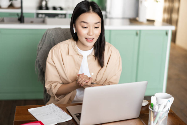 Young corporate woman working from home. Asian girl has online classes remotely, talking on video chat, internet lecture or webinar - Photo, Image