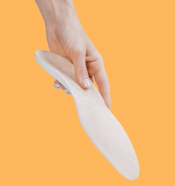 Orthopedic insole isolated on an orange background. Medical insoles. Treatment and prevention of flat feet and foot diseases. Foot care, feet comfort. Wear comfortable shoes. Flat Feet Correction - Фото, зображення