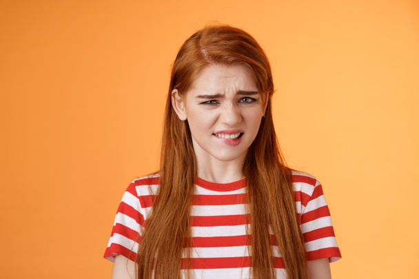 Cute disgusted redhead girl cringe from aversion bad awful smell, frowning grimace disappointed, clench teeth bothered, express dislike and reluctance, feel bad dissatisfied, refuse offer - Foto, afbeelding