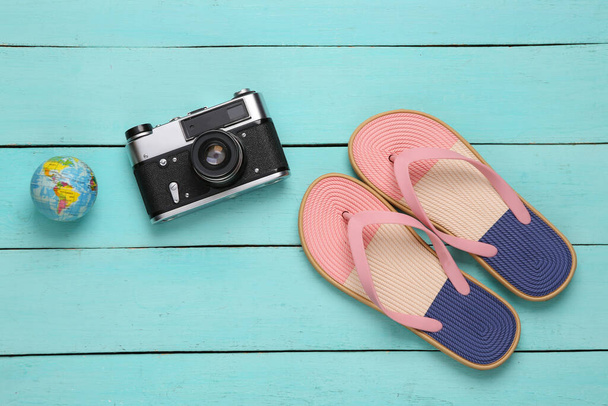 Chanclas de colores con accesorios de viaje sobre fondo de madera azul. Concepto de vacaciones en playa. Puesta plana - Foto, Imagen
