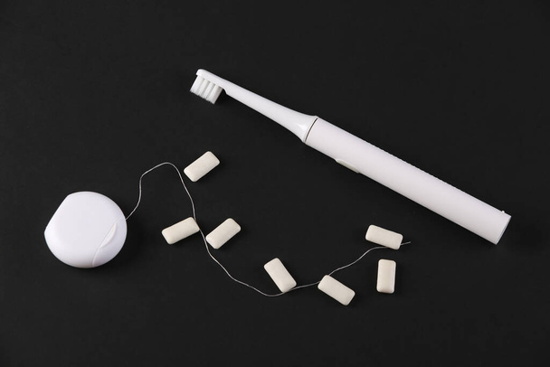 Концепція стоматологічної допомоги. Зубна щітка, зубна нитка та гумка на чорному тлі
 - Фото, зображення