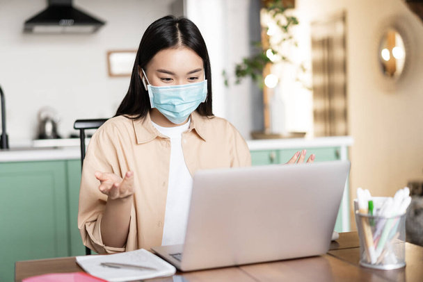 Young asian woman, student talking on video conference, attend lecture in medical face mask, online studying while on quarantine - Photo, Image