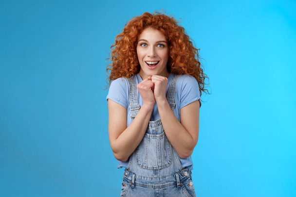 Tender silly sensitive redhead emotive curly girl clench hands together touched smiling gasping see heartwarming scene lovely puppy look camera fascinated delighted gaze impressed blue background - Photo, Image