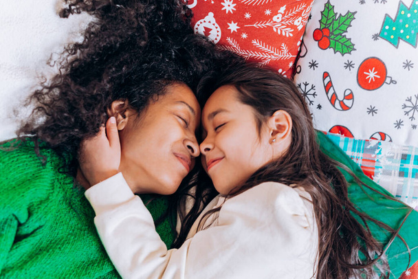 Mother and daughter lie and laugh on Christmas pillows - Fotografie, Obrázek