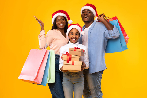 Gente negra feliz sosteniendo bolsas de compras y cajas de regalo de Navidad - Foto, imagen