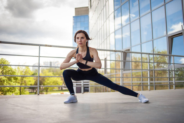 Jeune femme de fitness faisant des exercices d'échauffement près du bâtiment de la ville. mode de vie sain - Photo, image